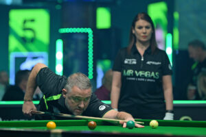 Stephen Hendry plays a shot with referee Michaela Tabb watching.